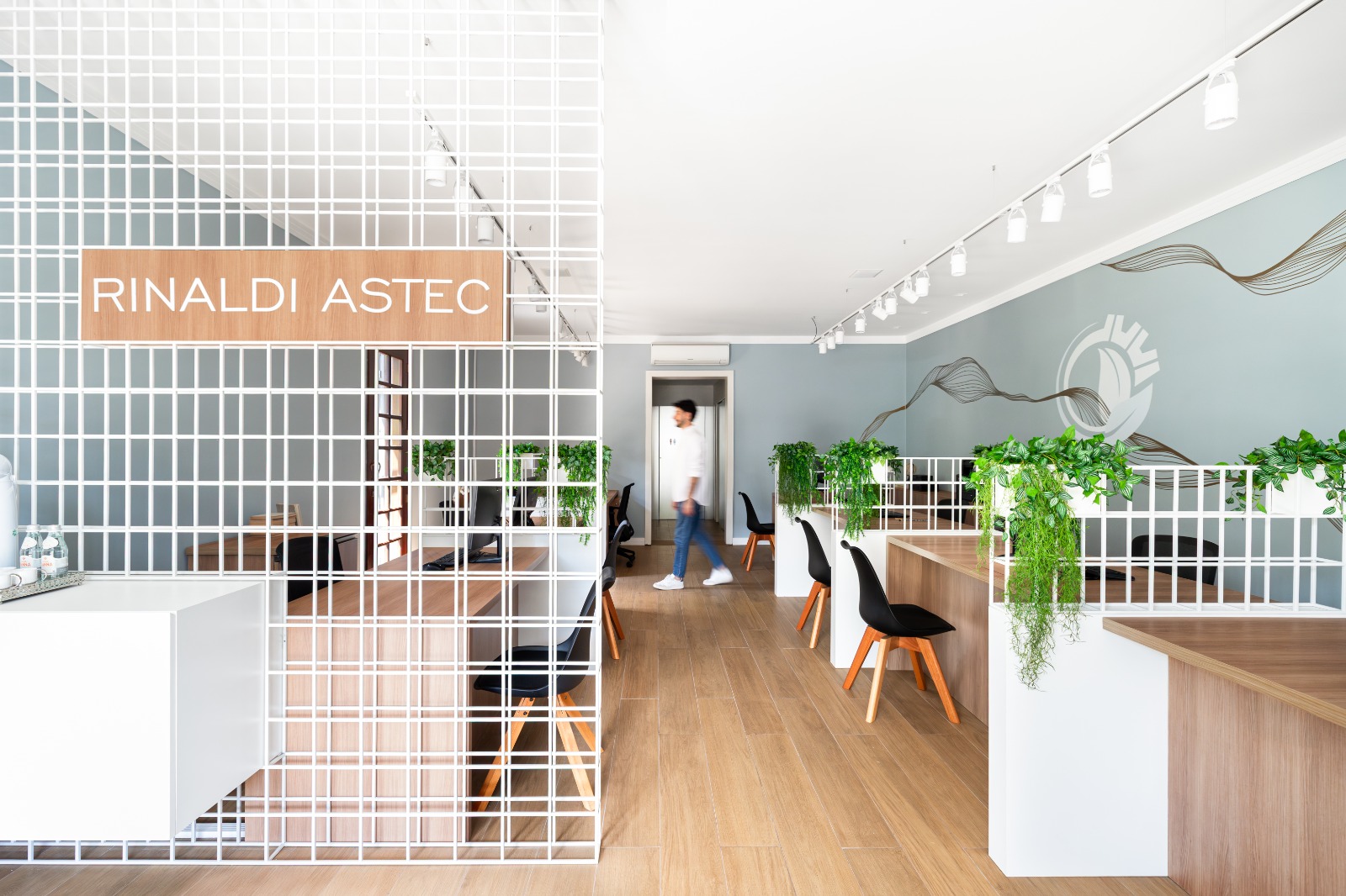 Placa Rinaldi Astec na grade da recepção e o corredor de atendimento com o emblema na parede